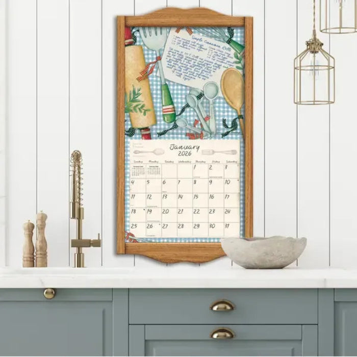 Framed calendar with kitchen-themed design on a white wall above a kitchen counter.