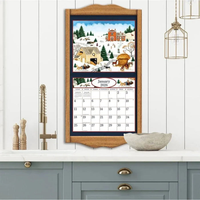 Framed calendar with winter scene design on a wall above a kitchen counter.