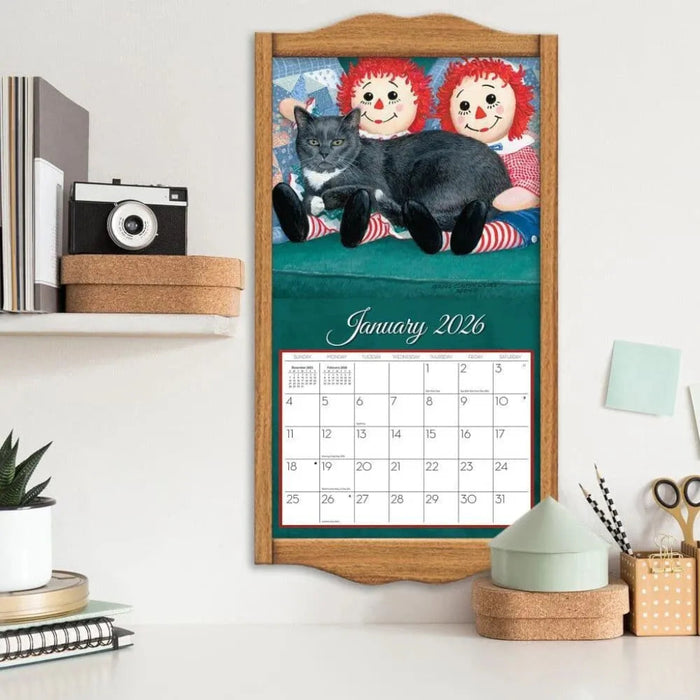Calendar with cartoon characters and a cat on a wooden frame, displayed on a shelf.