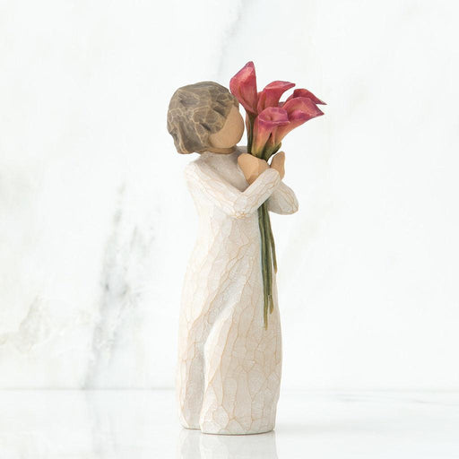 Statue of a woman holding pink lilies against a white background