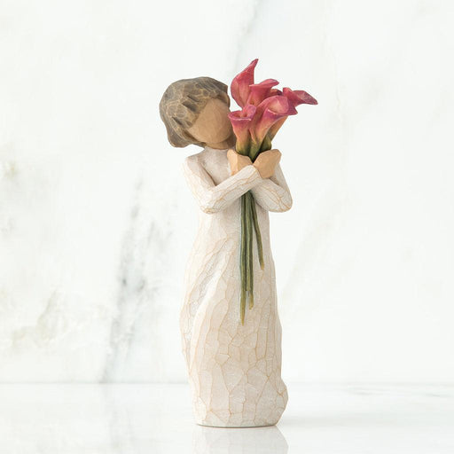 Statue of a woman holding pink flowers against a white background