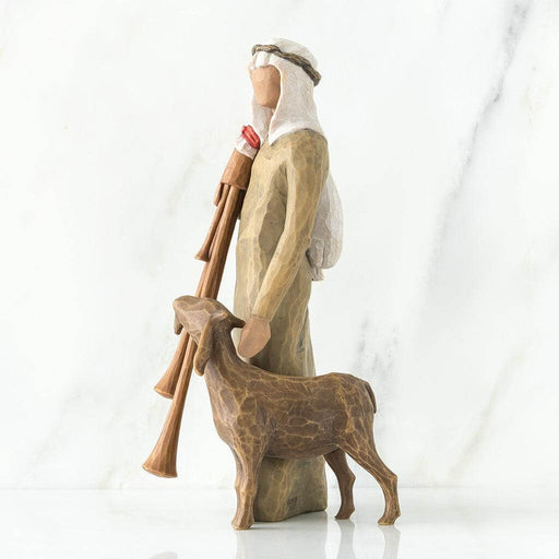 Wooden nativity scene figure of a shepherd with a lamb on a white background