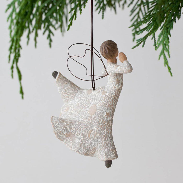 Decorative angel ornament with floral patterns hanging from a tree branch.