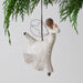 Decorative angel ornament with floral patterns hanging from a tree branch.