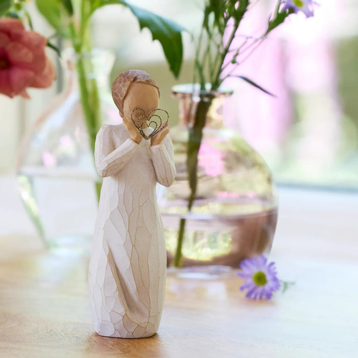 Decorative figurine holding a heart-shaped object on a blurred floral background