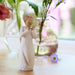 Decorative figurine holding a heart-shaped object on a blurred floral background