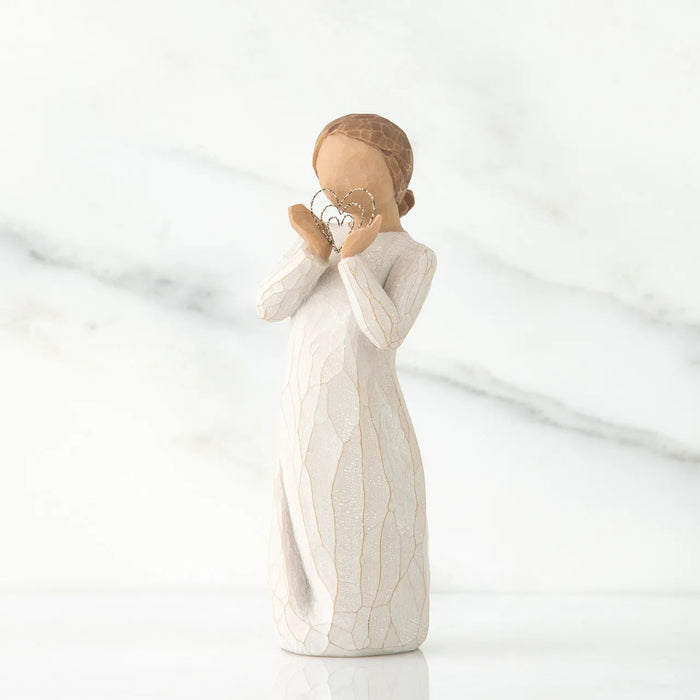 White  figurine of a woman holding a heart on a white background