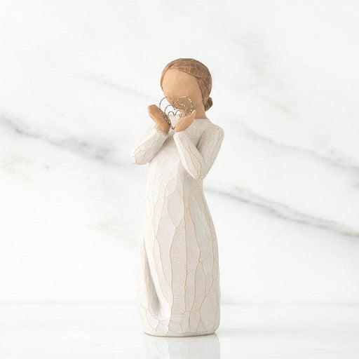 White figurine of a woman holding a delicate heart  on a white background