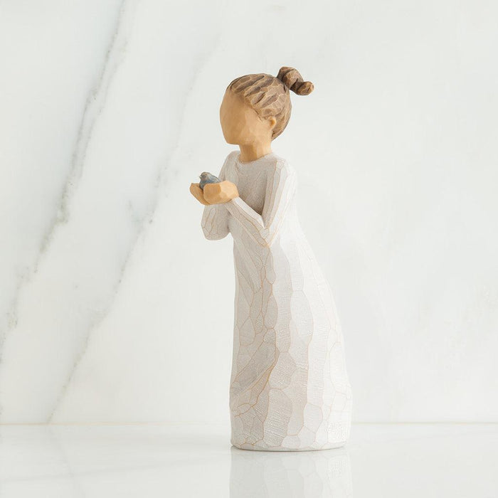 Figurine of a person holding a baby bird on a white background