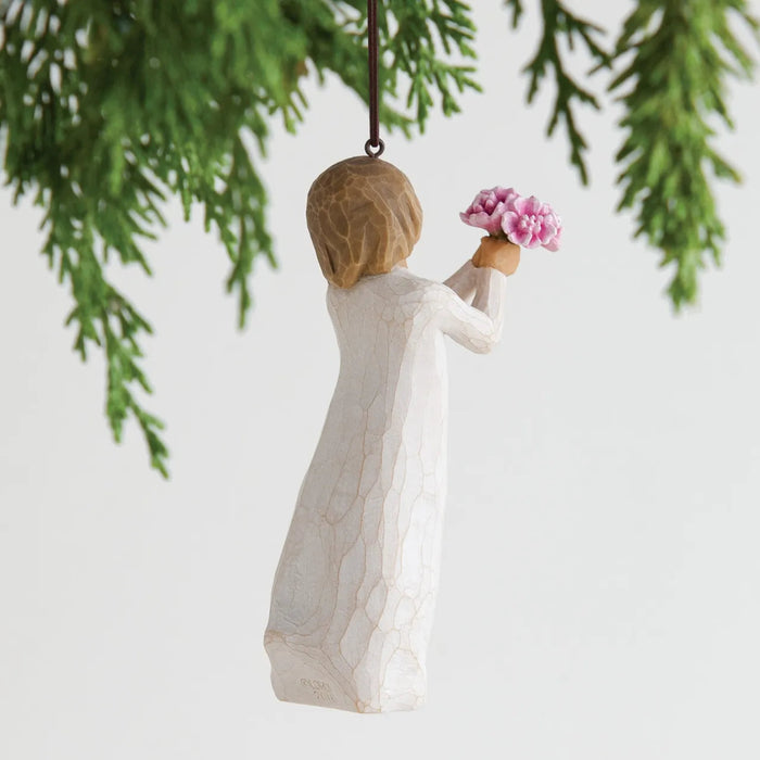 Decorative figurine of a woman holding flowers hanging from a tree branch.