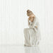 White ceramic figurine of a woman sitting with her child on a white background