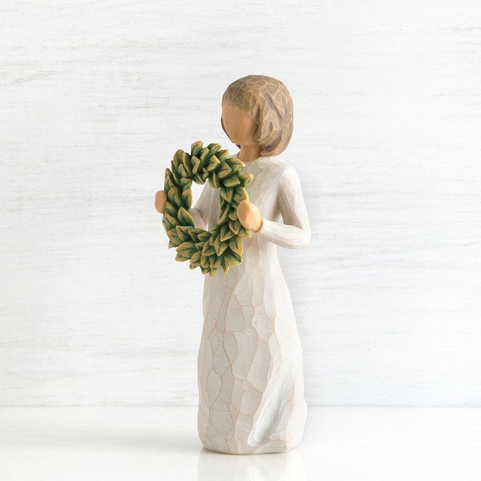 Decorative figurine of a woman holding a green wreath on a white background