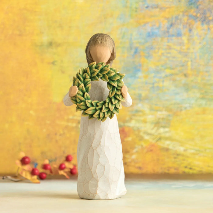 Decorative figurine of a woman holding a green wreath against a blurred autumn background.