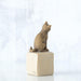 Stone sculpture of a cat on a white block with a white background