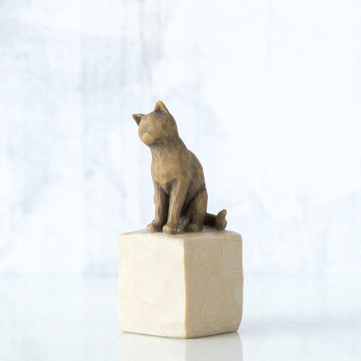 Bronze cat sculpture on a beige pedestal against a white background