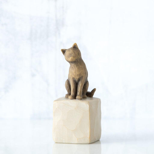Bronze cat sculpture on a white pedestal against a light gray background