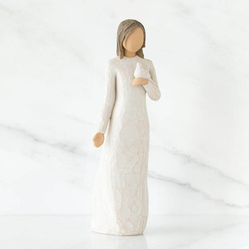Figurine of a woman in a long, light-colored dress holding a dove against a white background