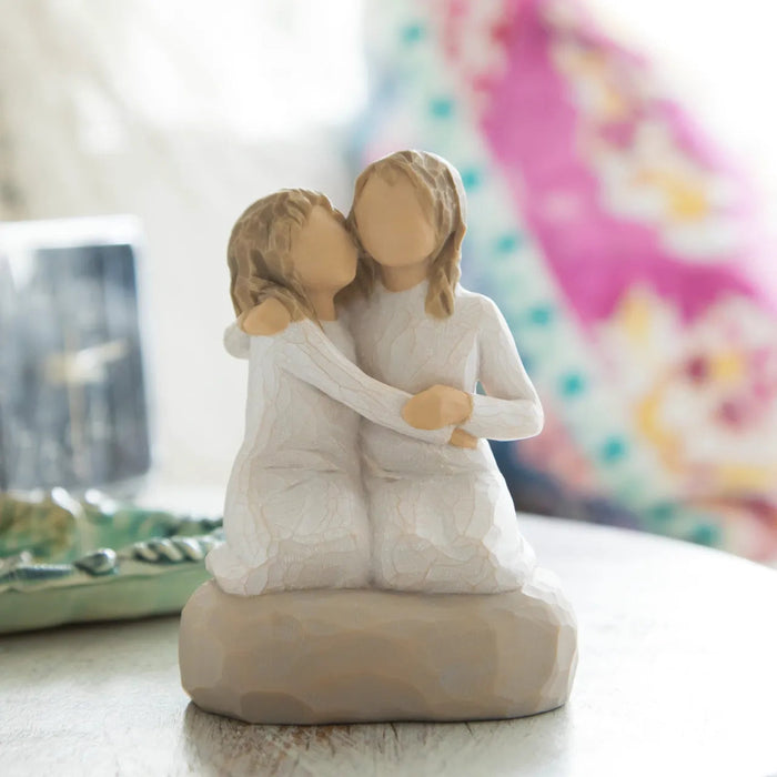 Willow Tree Sister Mine figurine showing two sisters sitting together on a table with a pinkish background 