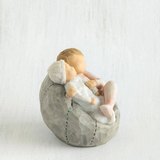 Small figurine of a baby sitting on a stone-like surface against a white background