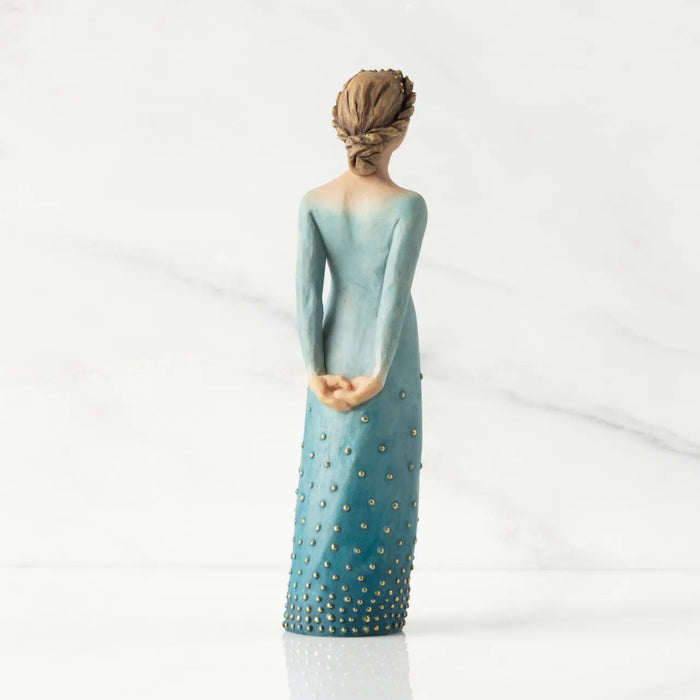 Figurine of a woman in a blue dress with gold accents on a white background