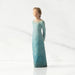 Figurine of a woman in a long, light blue dress with gold accents on a white background