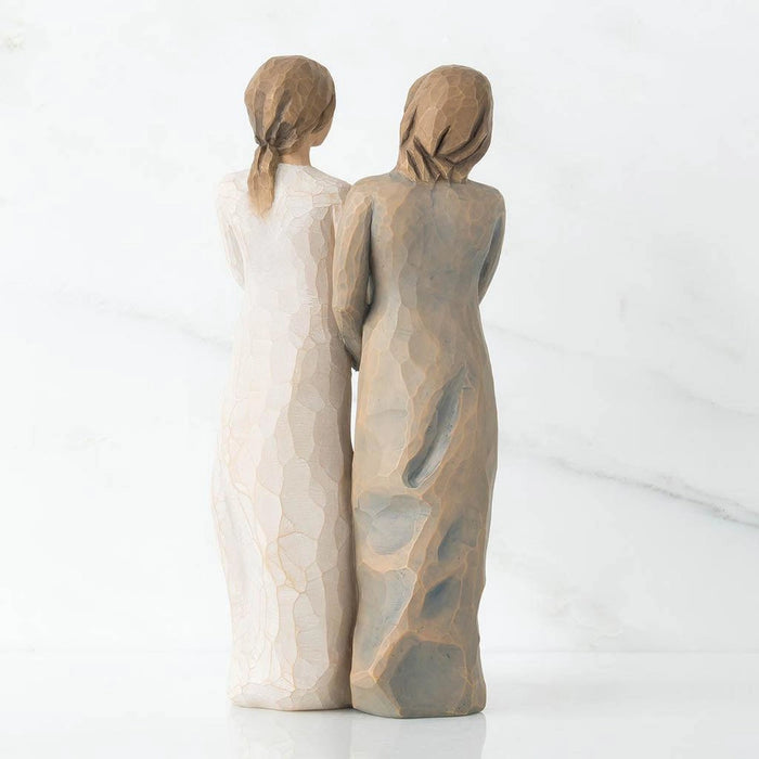 Two stone-like sculptures of women standing back-to-back on a white background