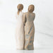 Two stone-like sculptures of women standing back-to-back on a white background