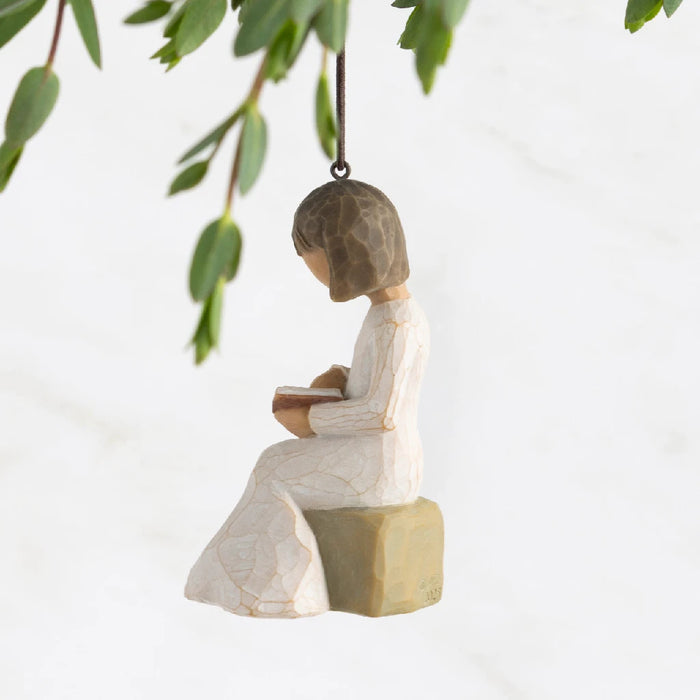 A whimsical ornament of a girl reading under a willow tree, representing a serene and imaginative outdoor setting.