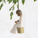 A whimsical ornament of a girl reading under a willow tree, representing a serene and imaginative outdoor setting.