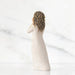 A figurine of a woman elegantly dressed in a flowing white gown, showcasing intricate details and graceful posture.