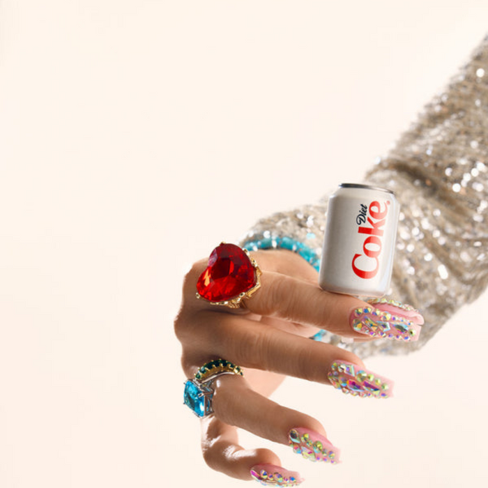 Hand holding the Nora Fleming Diet Coke® Can Mini with glamorous rings and rhinestone nails.