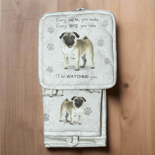 A set of kitchen mitts, pot holder, and a kitchen towel with a Pug dog design on a wooden surface.