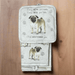 A set of kitchen mitts, pot holder, and a kitchen towel with a Pug dog design on a wooden surface.