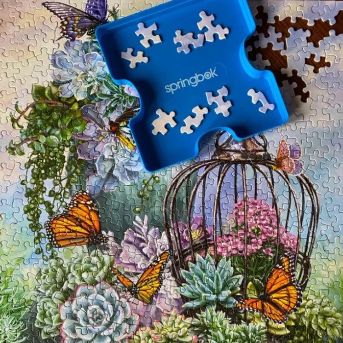Jigsaw puzzle with a blue puzzle piece holder labeled 'springbek' featuring a garden scene with butterflies.