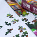Jigsaw puzzle with pieces scattered on a surface, featuring a 'The Library' theme.