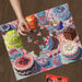 Puzzle with colorful cake illustrations on a wooden surface, featuring a hand placing a piece.