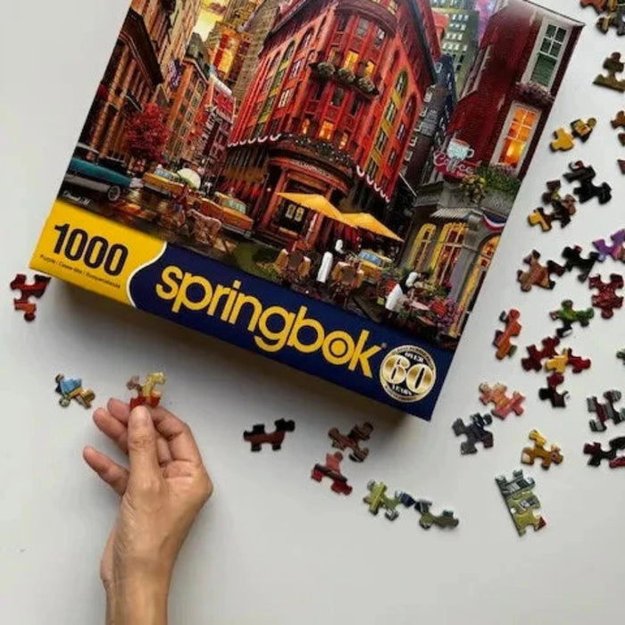 Springbok puzzle box with a colorful cityscape design, partially completed puzzle on a white surface.