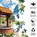 Jigsaw puzzle with a garden scene featuring a well and blue house, with brand logos and product features displayed.