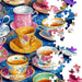 Colorful teacups and saucers on a blue surface with puzzle pieces scattered around, featuring Springbok brand.