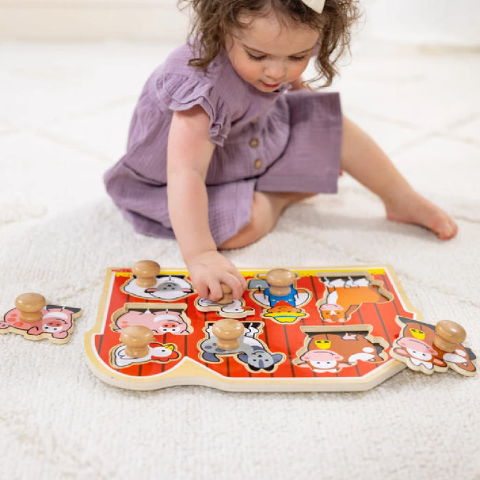 A wooden puzzle board with cut-out shapes of farm animals, including a cow, pig, and chicken, for educational play.