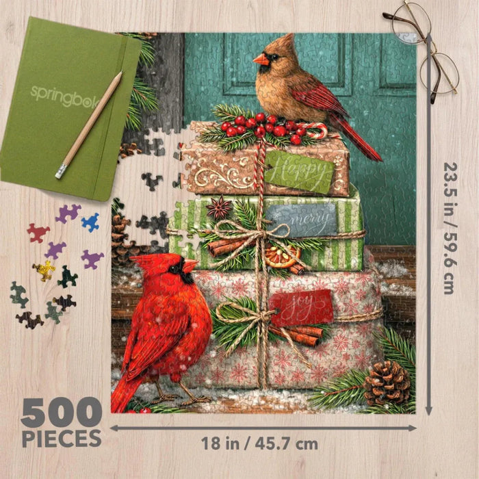 This Springbok Cardinal Couriers 500 Piece Jigsaw Puzzle features a fleet of bright red cardinal birds delivering mail across a snowy winter scene. 