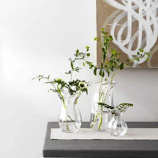 A clear glass vase characterized by a flowing wavy design, emphasizing its stylish and contemporary appearance.