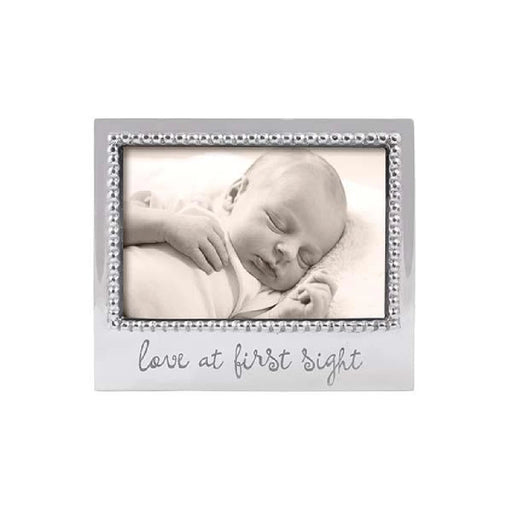 A sleeping baby in a silver frame, with the phrase "love at first sight" elegantly displayed above the image.