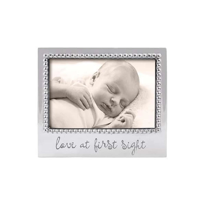 A sleeping baby in a silver frame, with the phrase "love at first sight" elegantly displayed above the image.