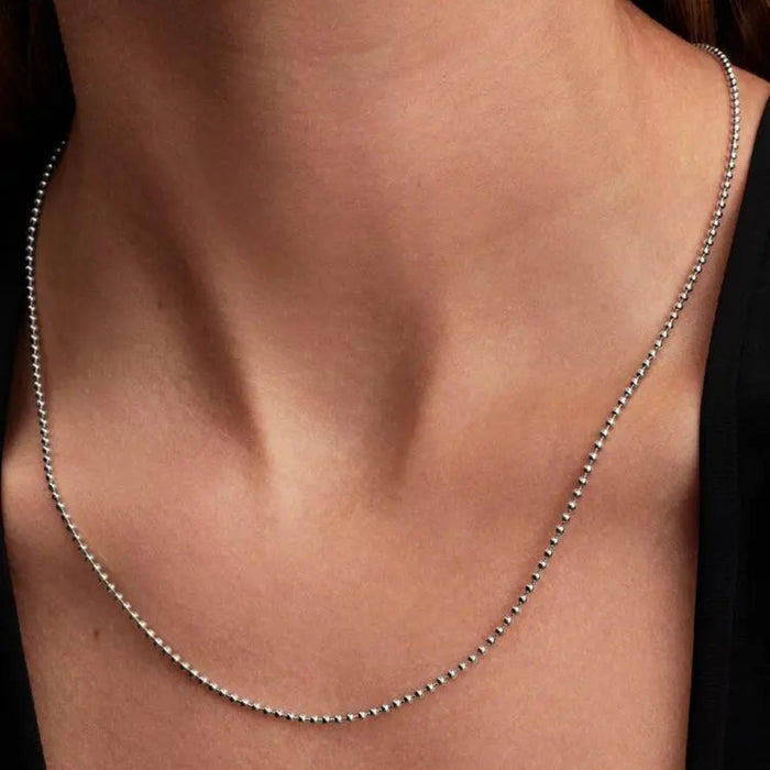 Close-up of a woman’s neck wearing the Pandora Ball Chain Necklace, a modern sterling silver beaded chain.