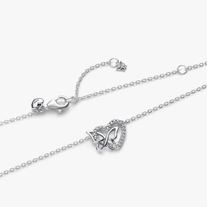 Silver necklace with a heart and butterfly shaped charm on a white background