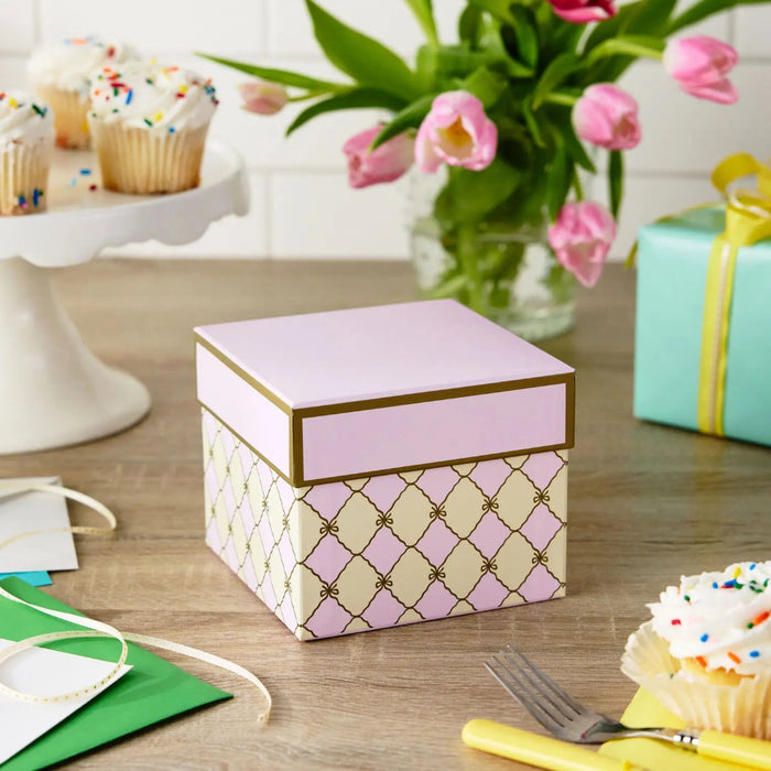Medium pink‑and‑cream gift box with gold accents displayed on a table