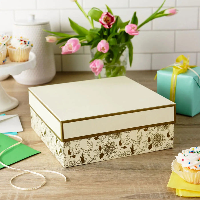 Large floral gift box with gold accents and white lid displayed on a party table 