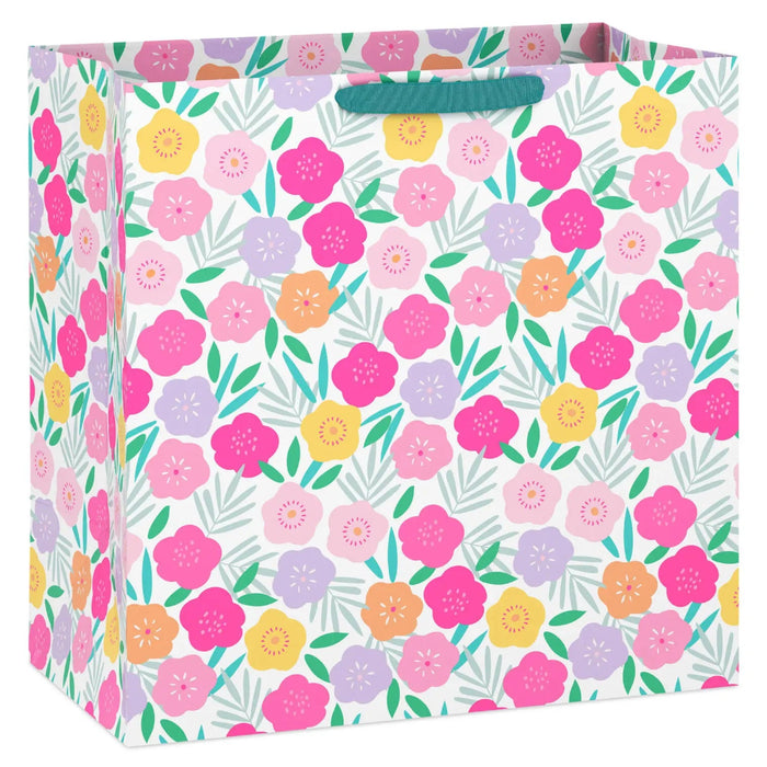 Extra‑deep white gift bag with vibrant floral print in pink, purple, yellow, and orange; grosgrain ribbon handles