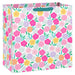 Extra‑deep white gift bag with vibrant floral print in pink, purple, yellow, and orange; grosgrain ribbon handles